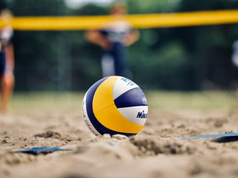 yellow and white volleyball on brown sand during daytime